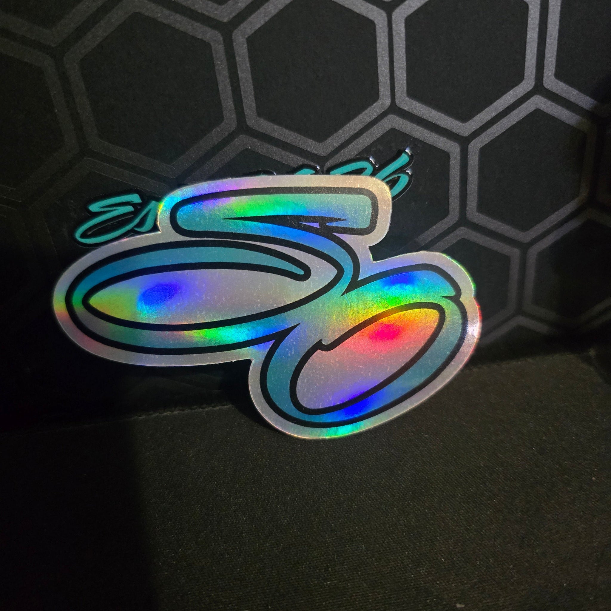 Holographic sticker with colorful design on a dark textured background